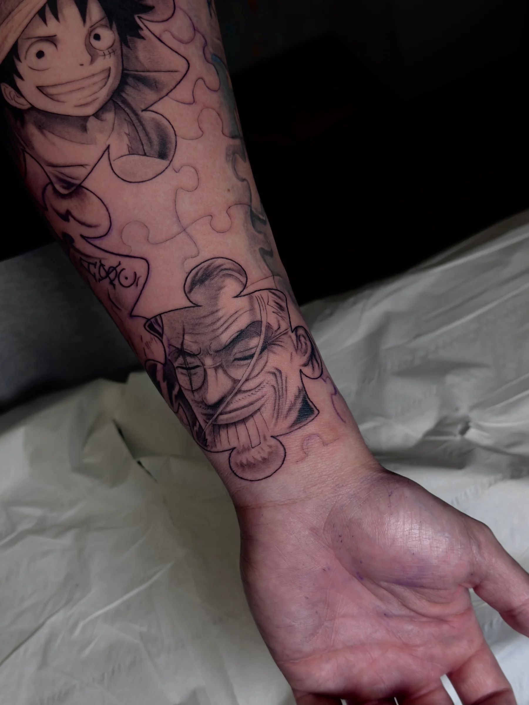 Luffy y otro personaje de One Piece sobre un puzle, en el antebrazo