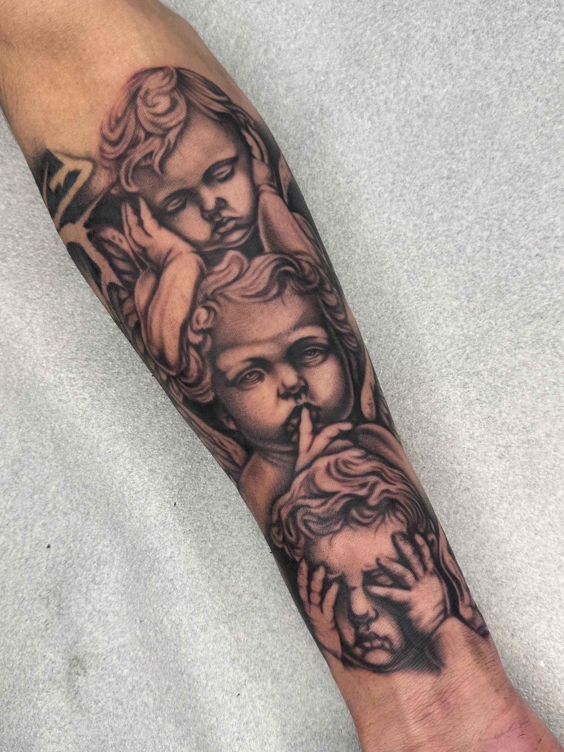 Tres angelitos que se tapan los ojos, la boca y los oídos, en el antebrazo