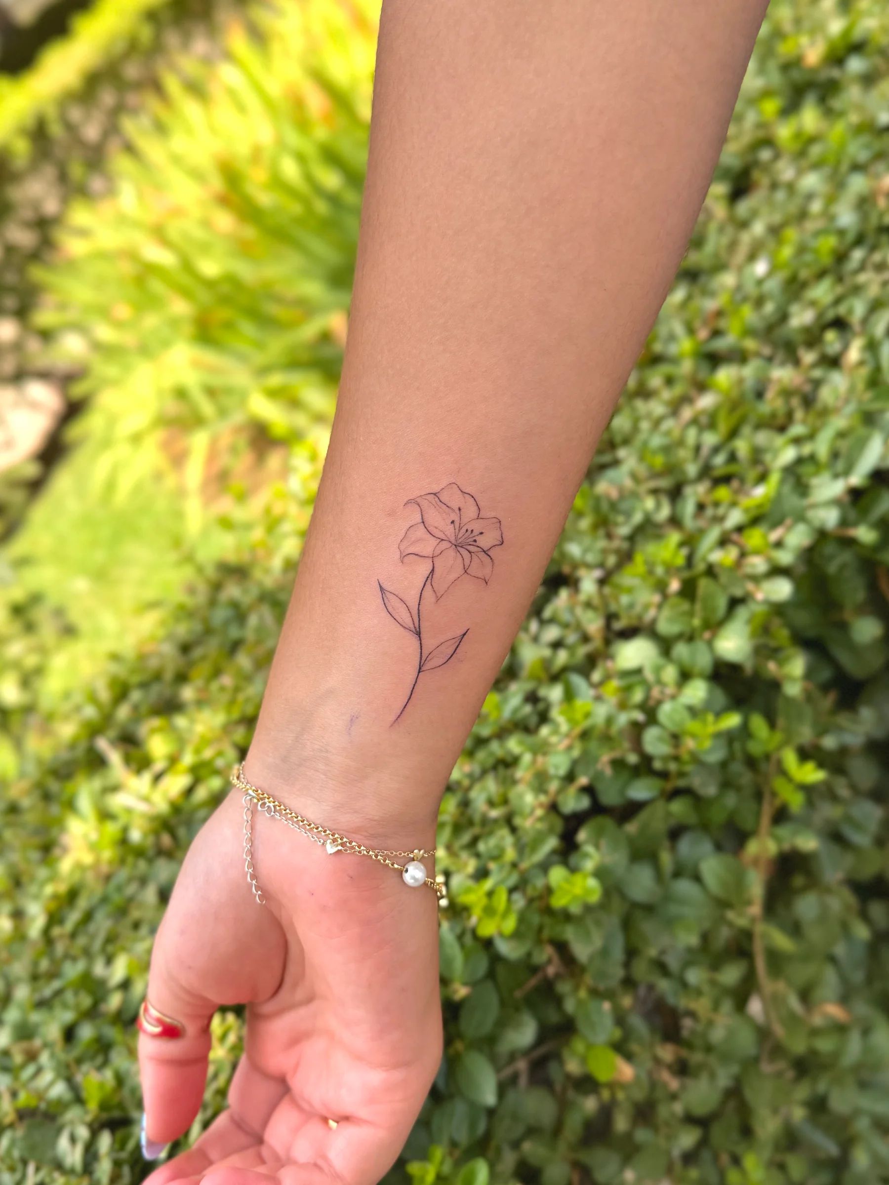 Flor de trazo fino en el antebrazo, cerca de la muñeca