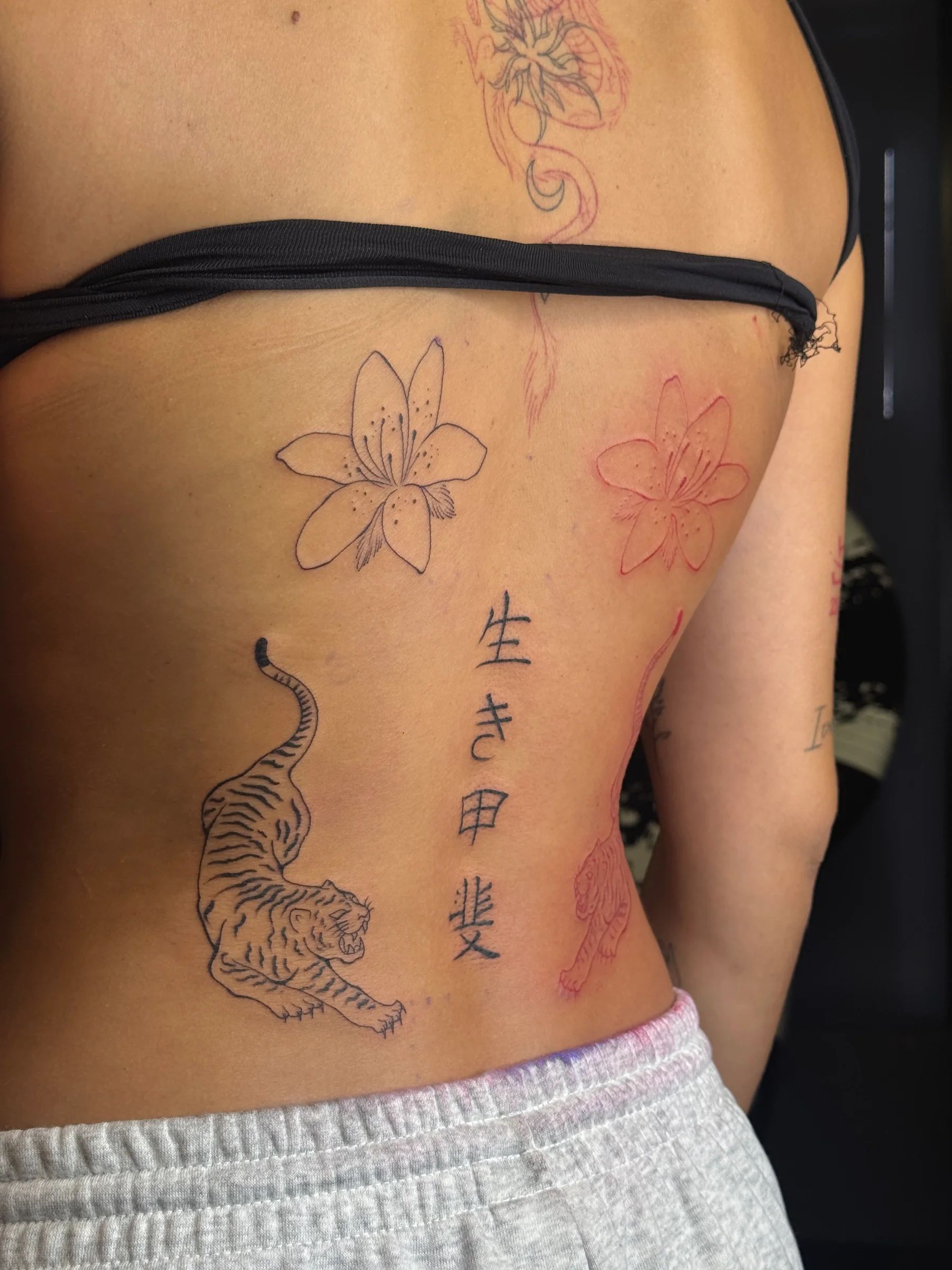 Lirio, tigre, flores en rojo y letras japonesas en la espalda