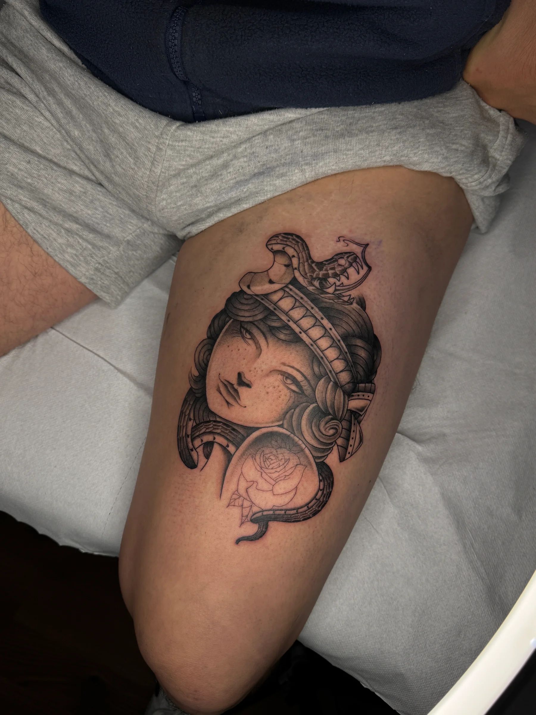 Cabeza de mujer con una serpiente y una rosa en el muslo