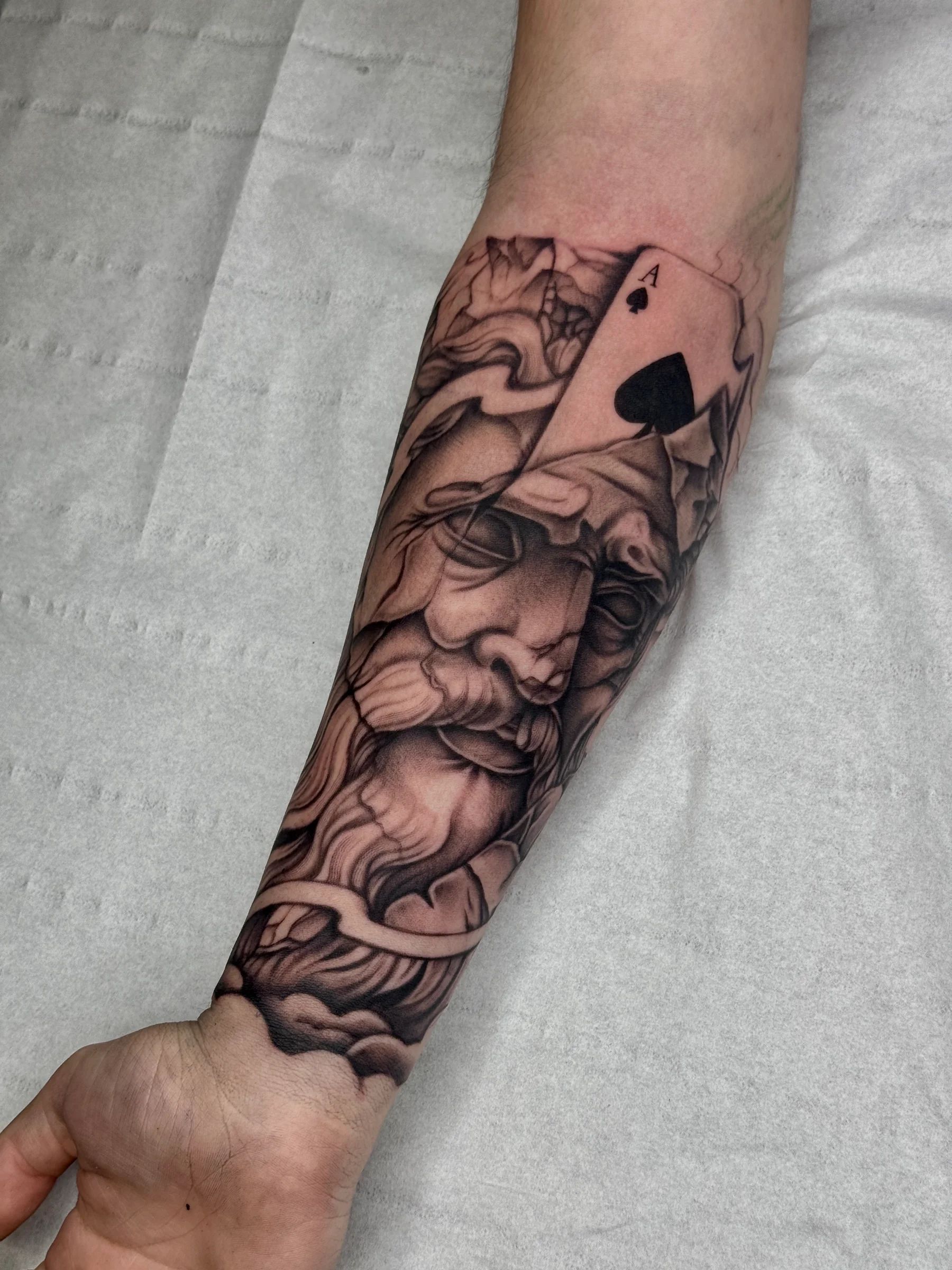 Rostro de estatua con un as de picas en el antebrazo